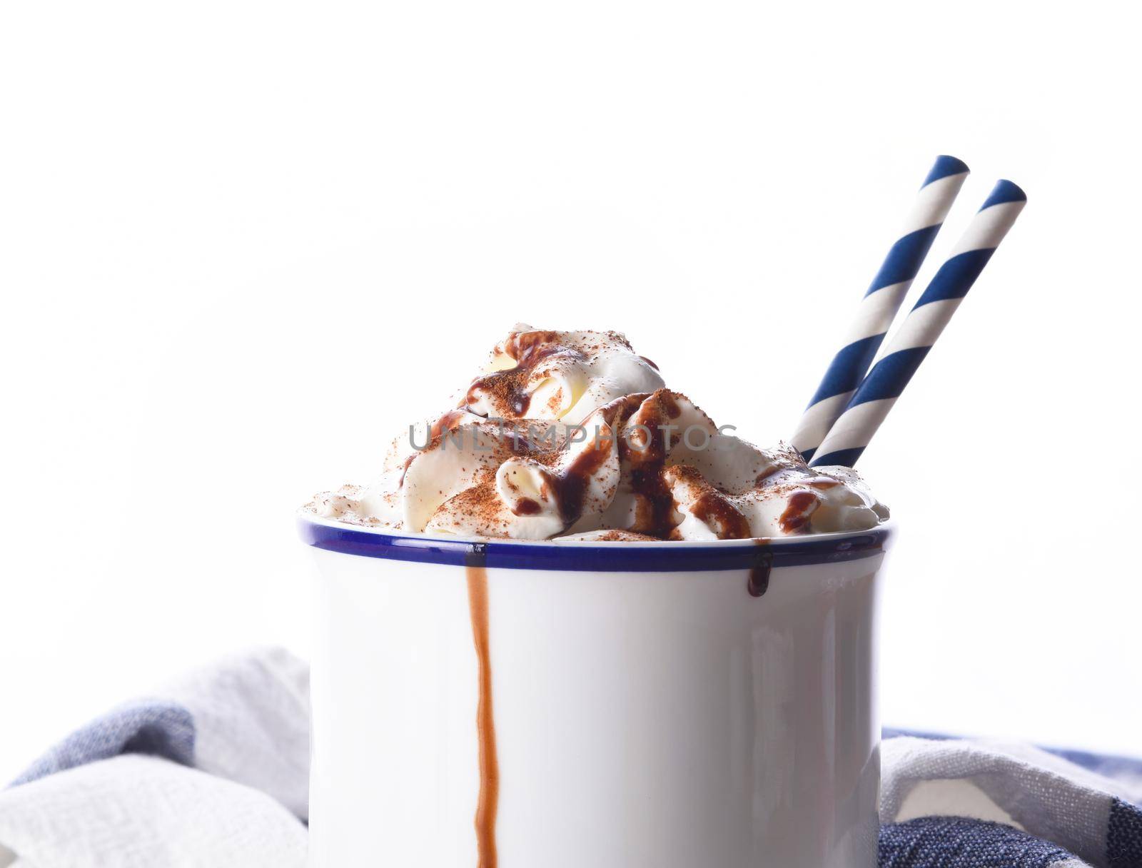 Closeup of a mug of hot chocolate with whipped cream and two paper drinking straws by sCukrov