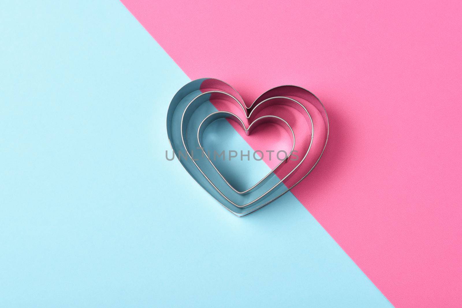 Valentines Day Concept: Nested Heart shaped cookie cutters on pink and blue with copy space. by sCukrov