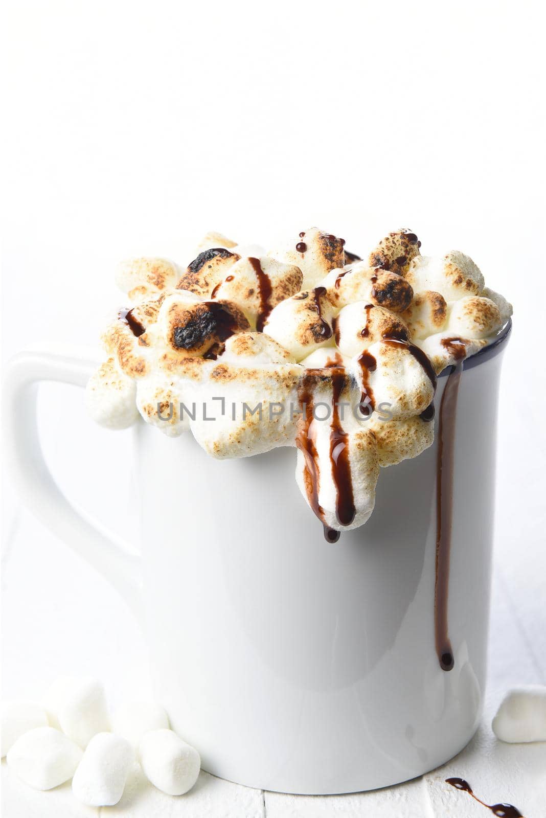 Closeup of a mug of hot cocoa with toasted marshmallows on a white background. 