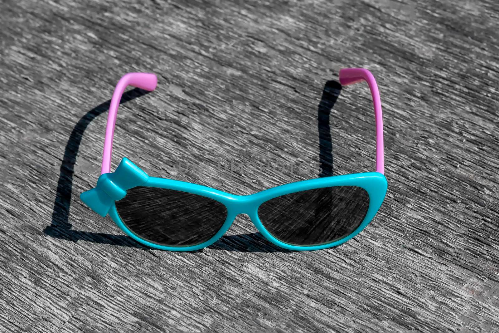 Blue sunglasses with pink arches on gray background. by Essffes