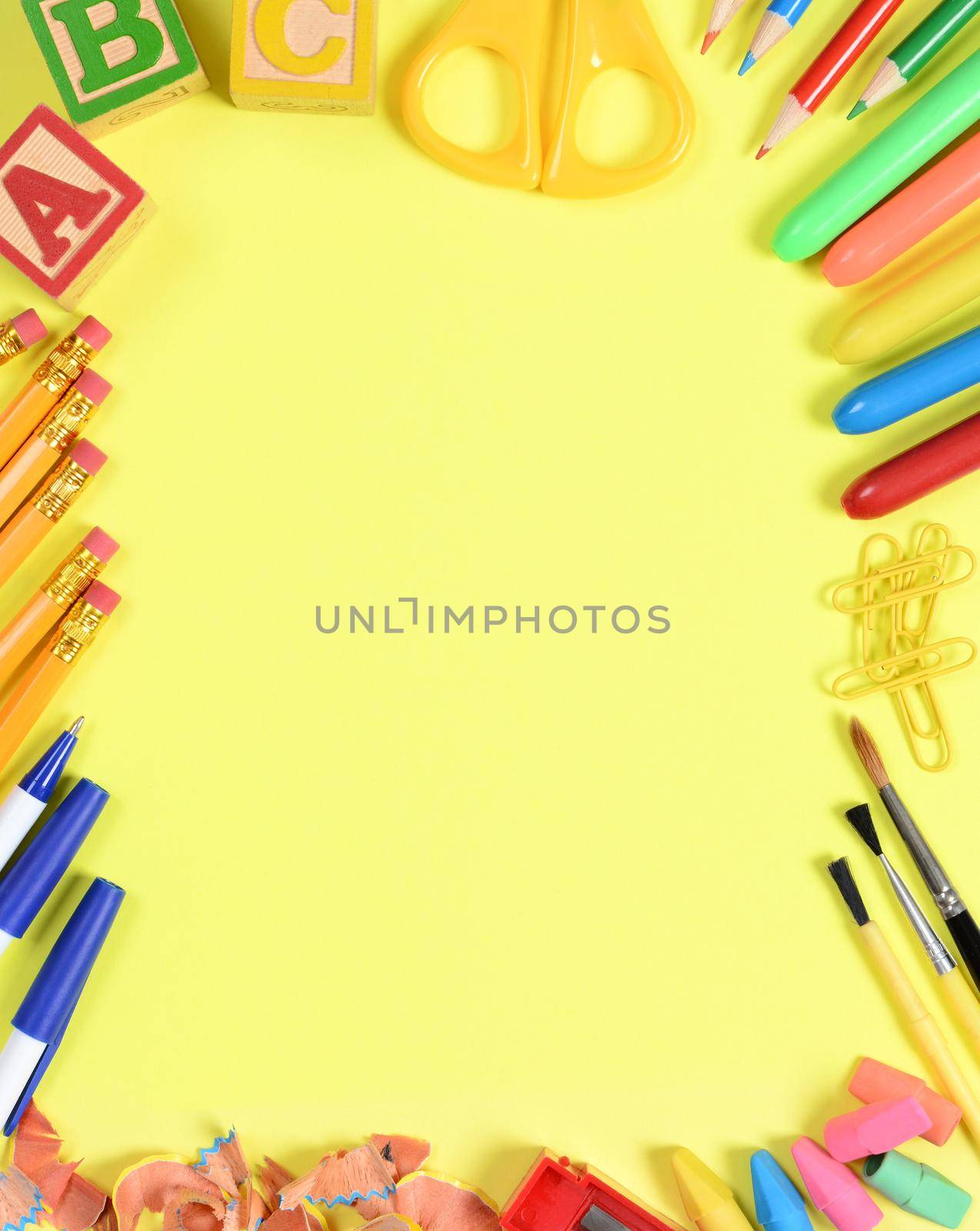 School supplies arranged on the outer edge of a yellow background. Center is blank for your own copy.