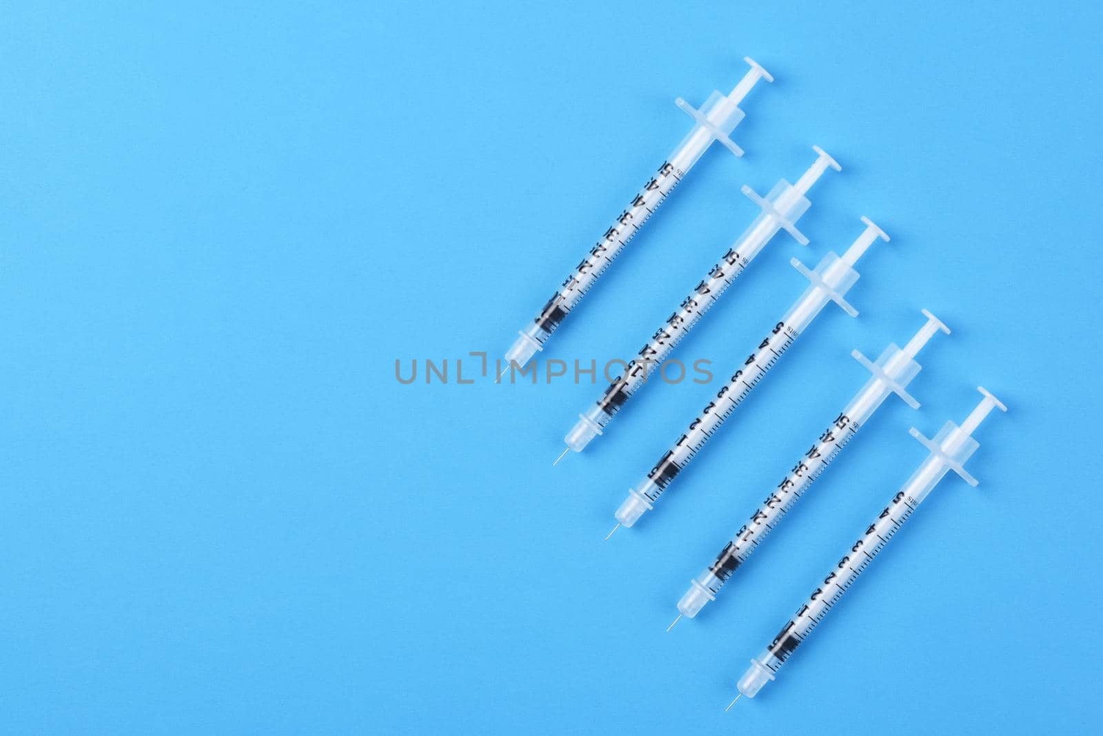 Five new syringes on a blue background with copy space. by sCukrov
