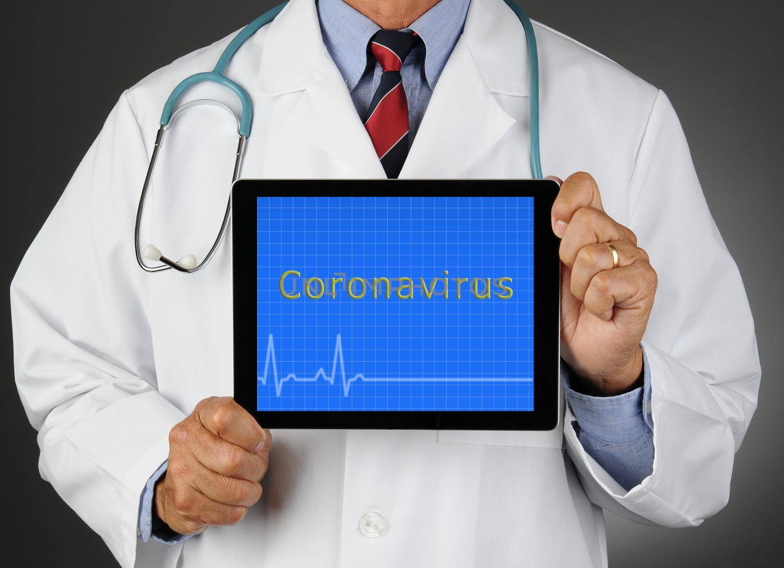 Closeup of a doctor holding a tablet computer with Coronavirus written on the screen.  Horizontal format over a light to dark gray background. Man is unrecognizable.