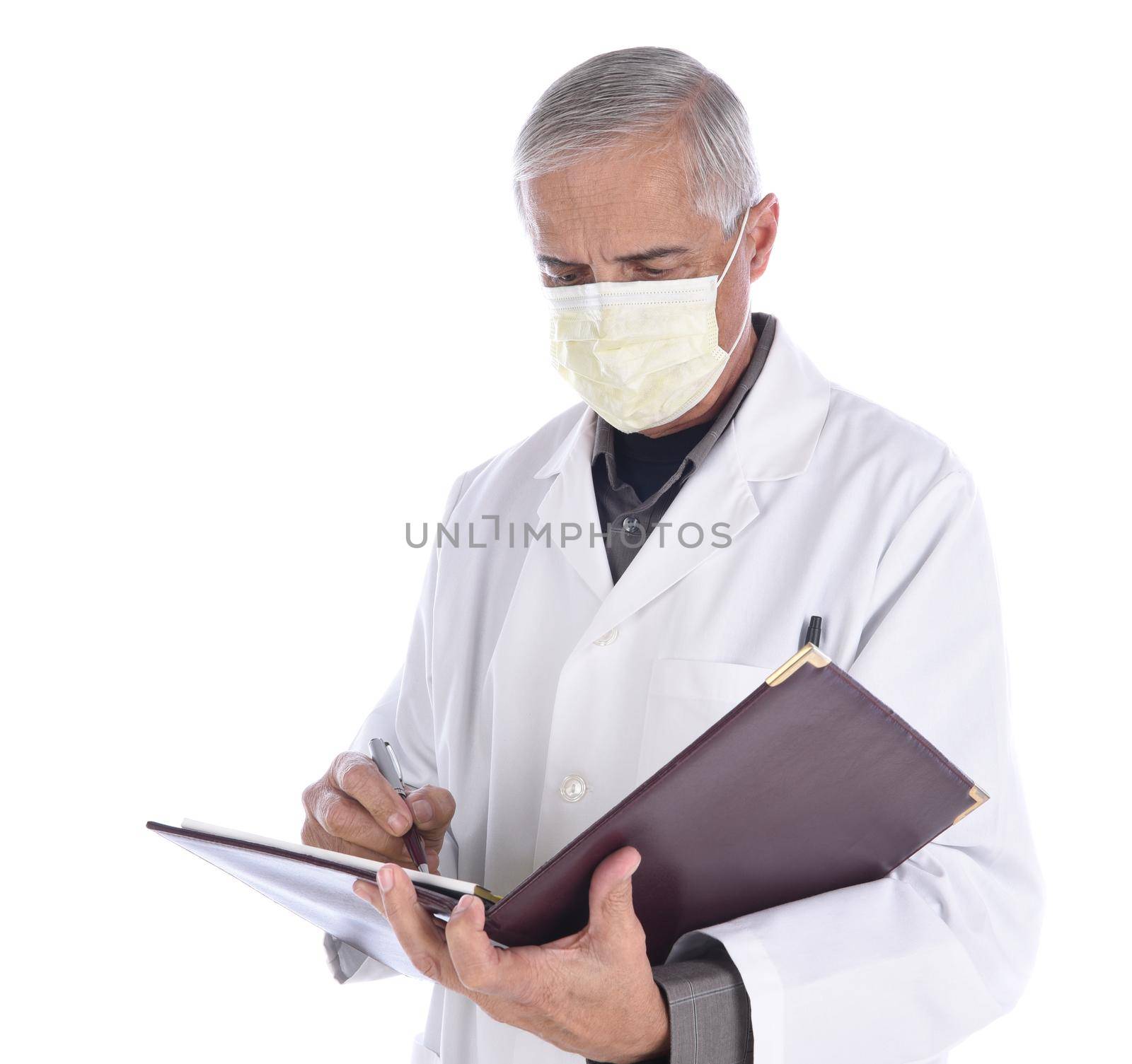 Portrait of a middle aged doctor wearing a surgical mask and lab coat looking down as he writes in a notebook. Isolated on white. by sCukrov