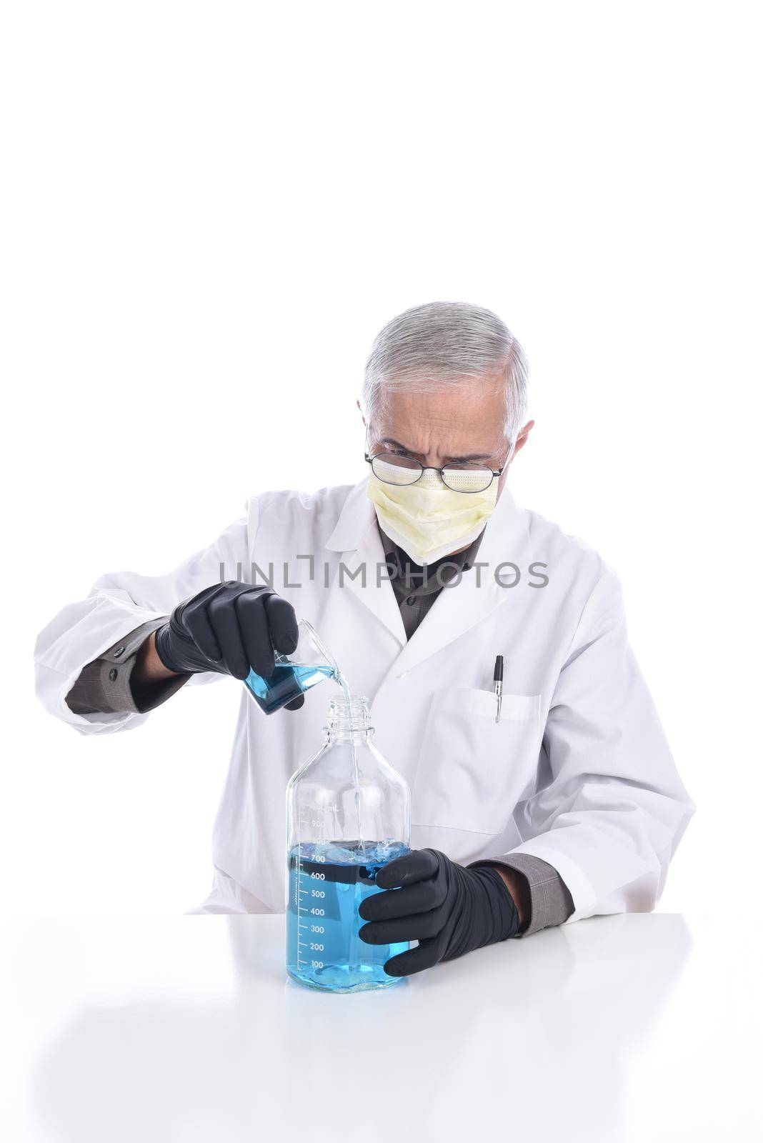 A lab tech pouring liquid from one vessel into another. Man is wearing a protective mask and gloves, isolated on white.