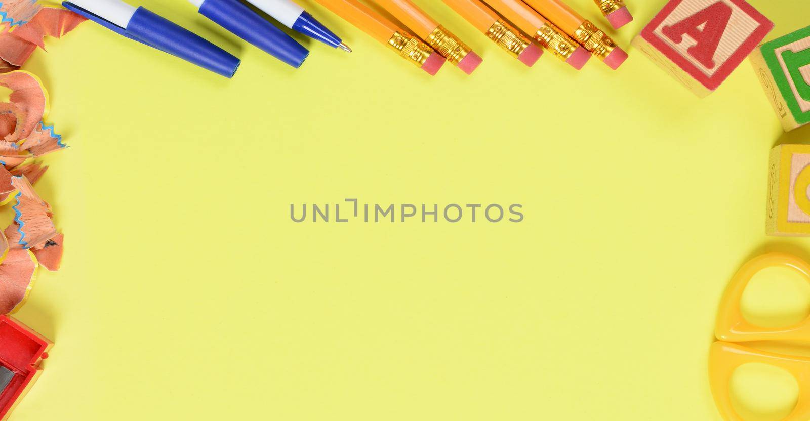 Back to school concept: School supplies on a yellow background with copy space. Bannr sized image.