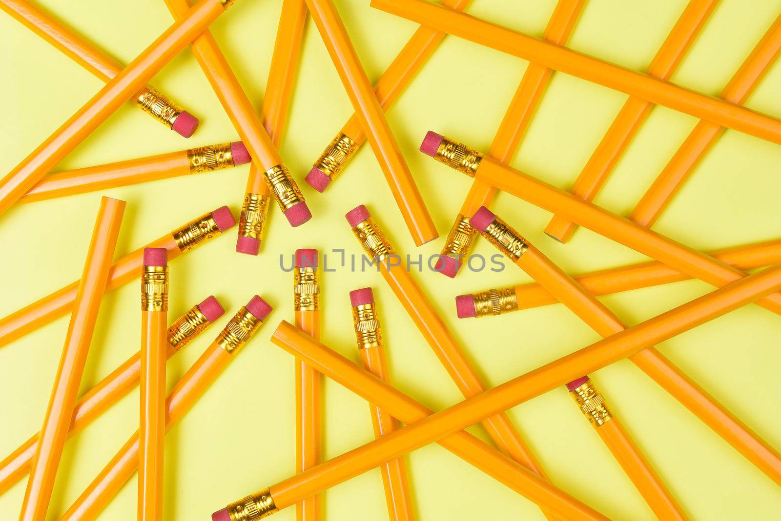 Back to School theme: Top view of a group of pencils on a yellow background filling the frame.