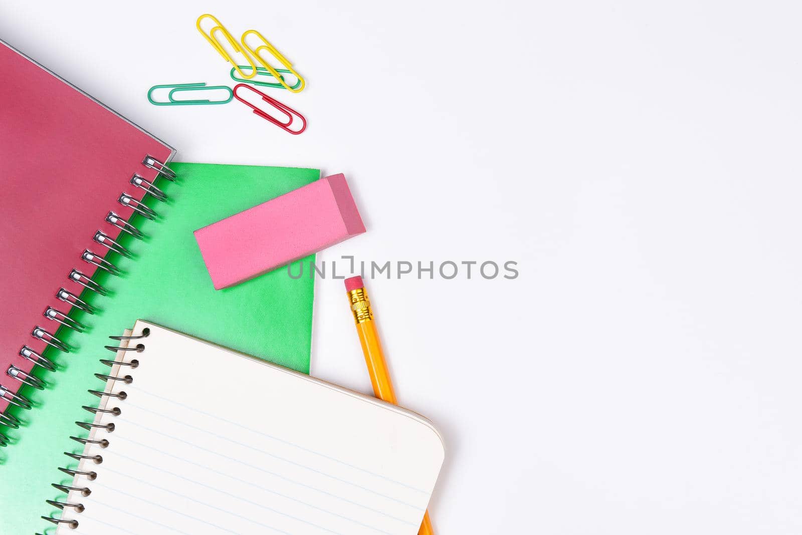 School Supplies: Notebooks pencil and paper clips on a white background.