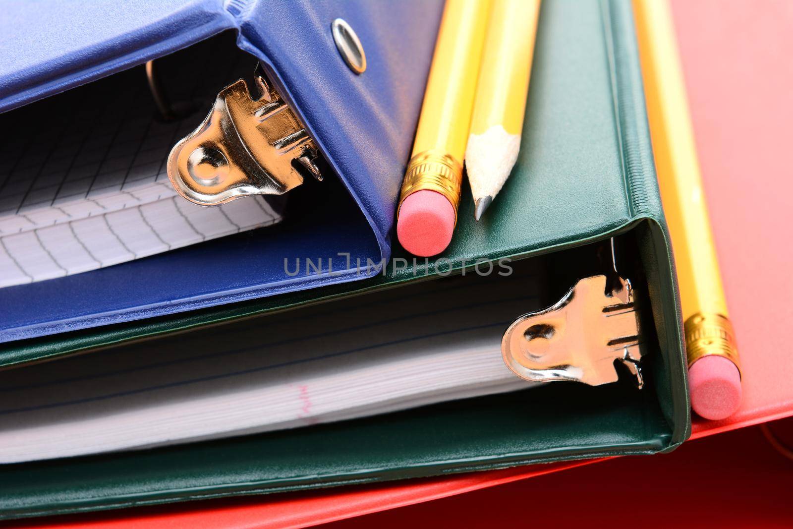 Closeup of three ring binders and pencils. Shallow depth of field in horizontal format filling the frame.