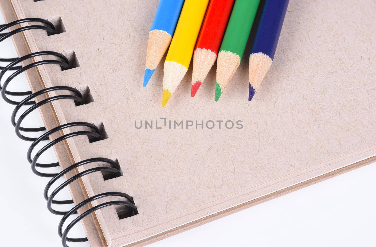 Colored Pencils: Closeup of five sharpened colorful pencils on a sketch book.