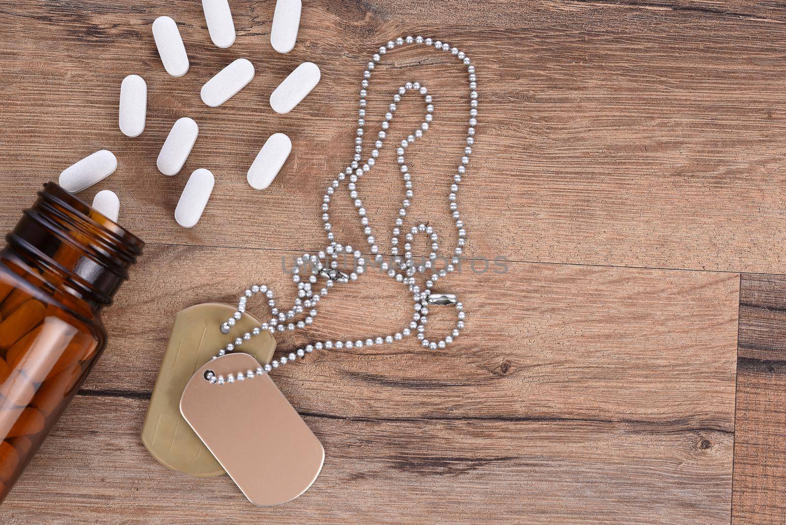 Military and Veterans Health Care Concept. Dog tags and pills on a wood background with copy space.