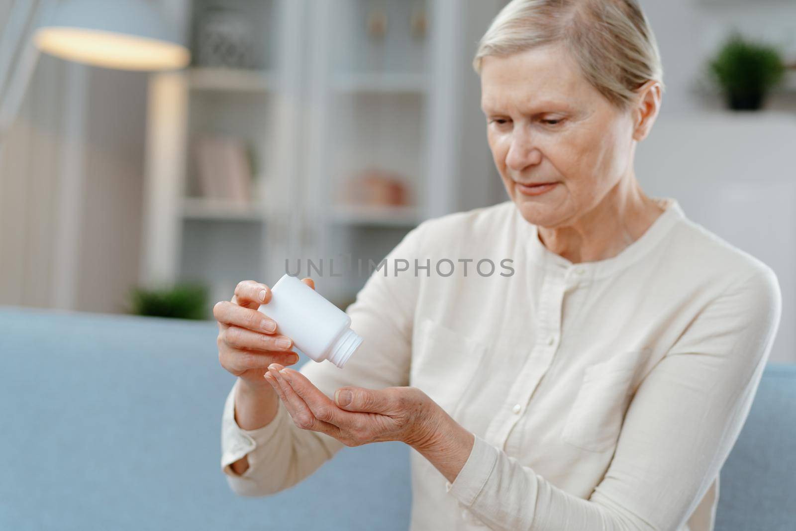 Serious mature woman taking out pills from bottle . close up