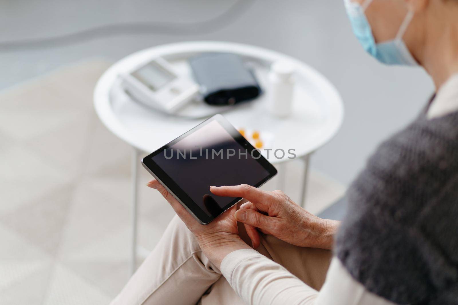 sick woman with a digital tablet sitting on the couch. by SmartPhotoLab