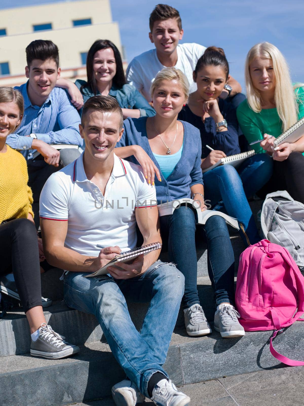 Group portrait  of happy  students outside sitting on steps have fun