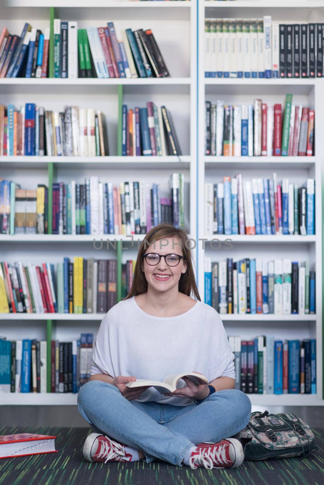 famale student reading book in library by dotshock