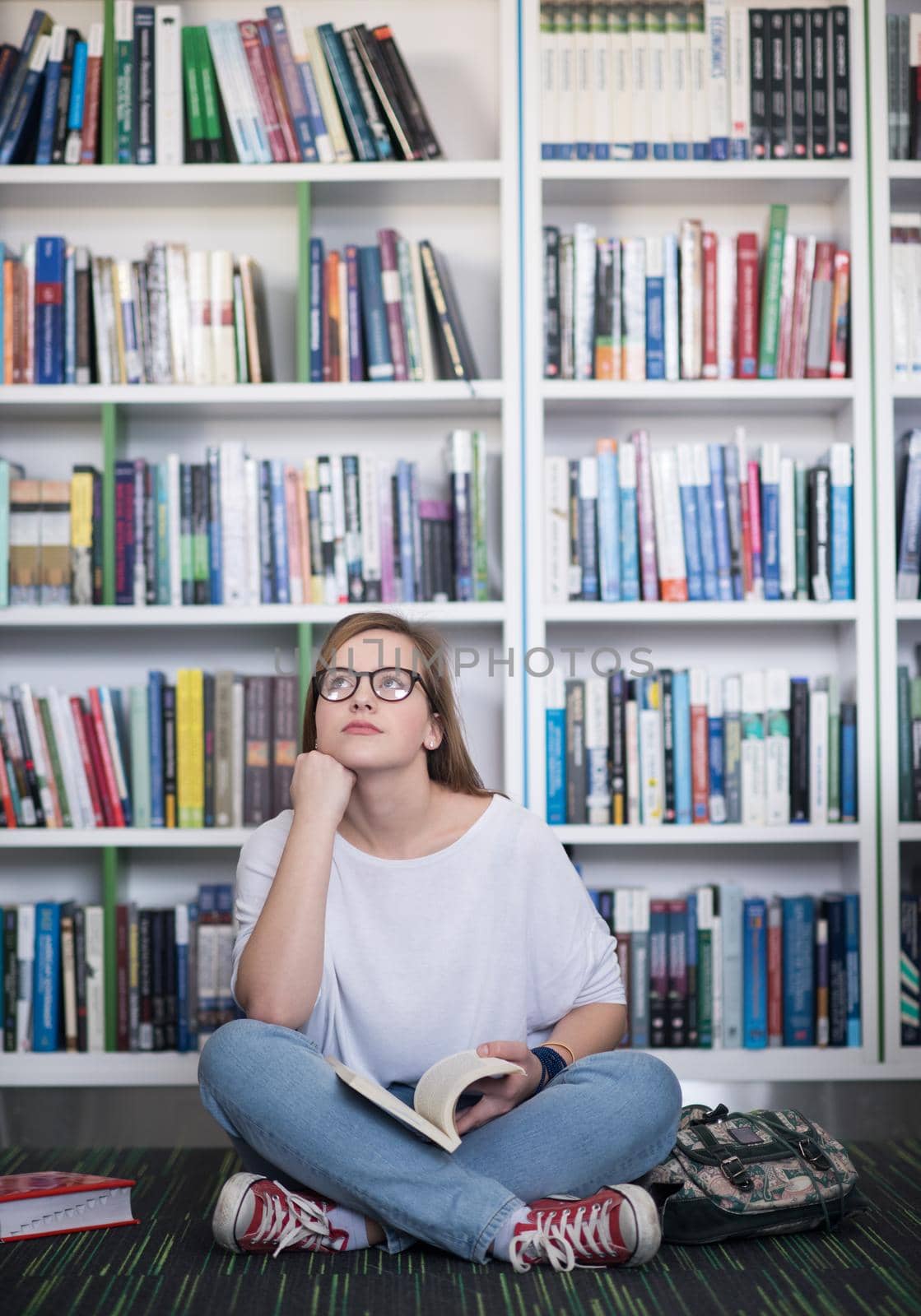 famale student reading book in library by dotshock