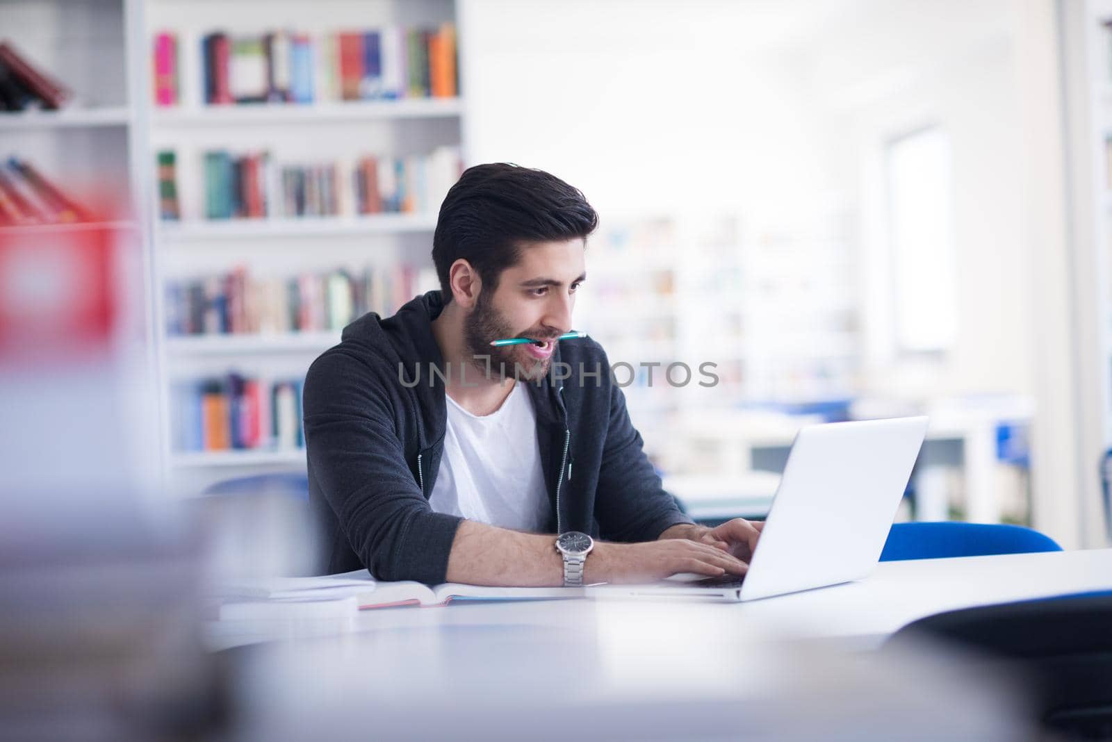 student preparing exam and learning lessons in school library, making research on laptop and browse internet