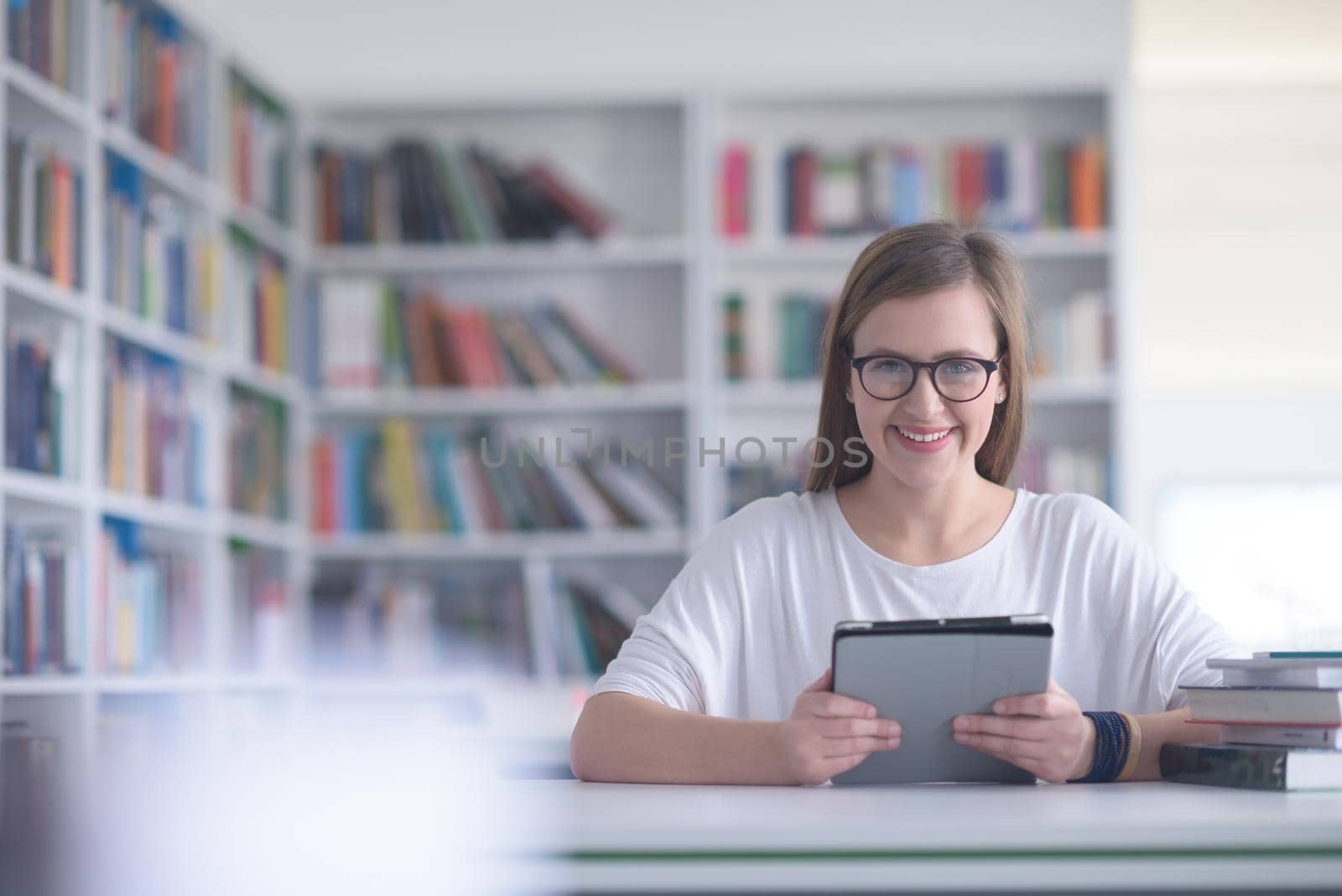female student study in school library, using tablet  and searching for informations on internet