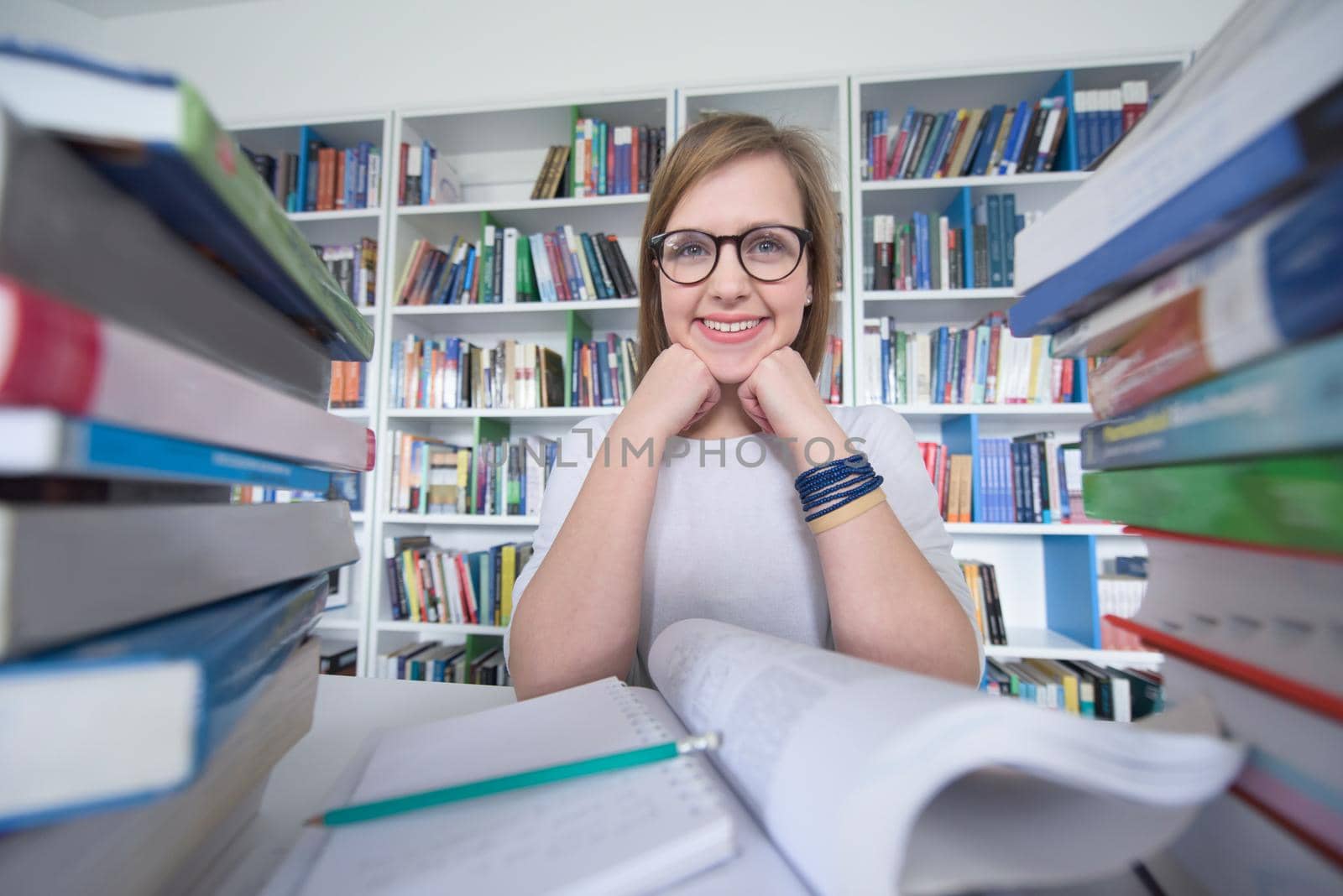 female student study in school library, using tablet and searching for information’s on internet. Listening music and lessons on white headphones