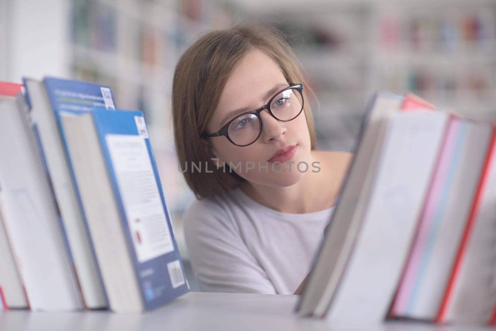 portrait of famale student selecting book to read in library by dotshock