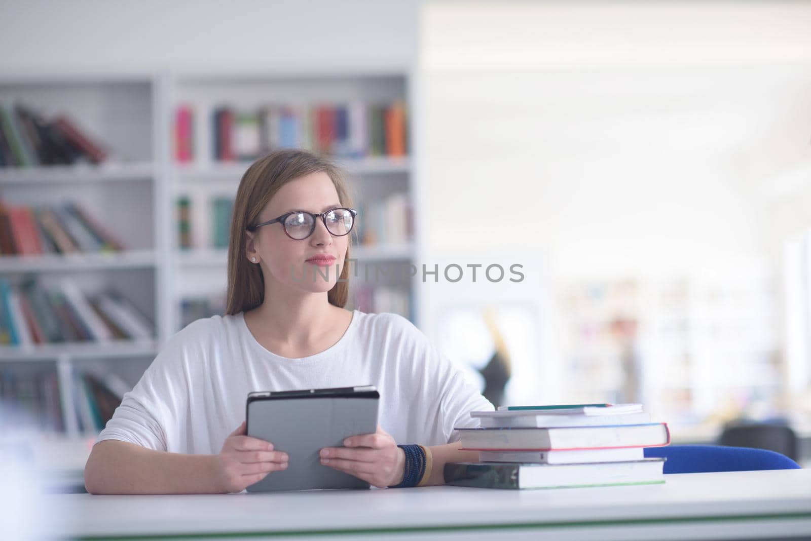 female student study in school library, using tablet by dotshock