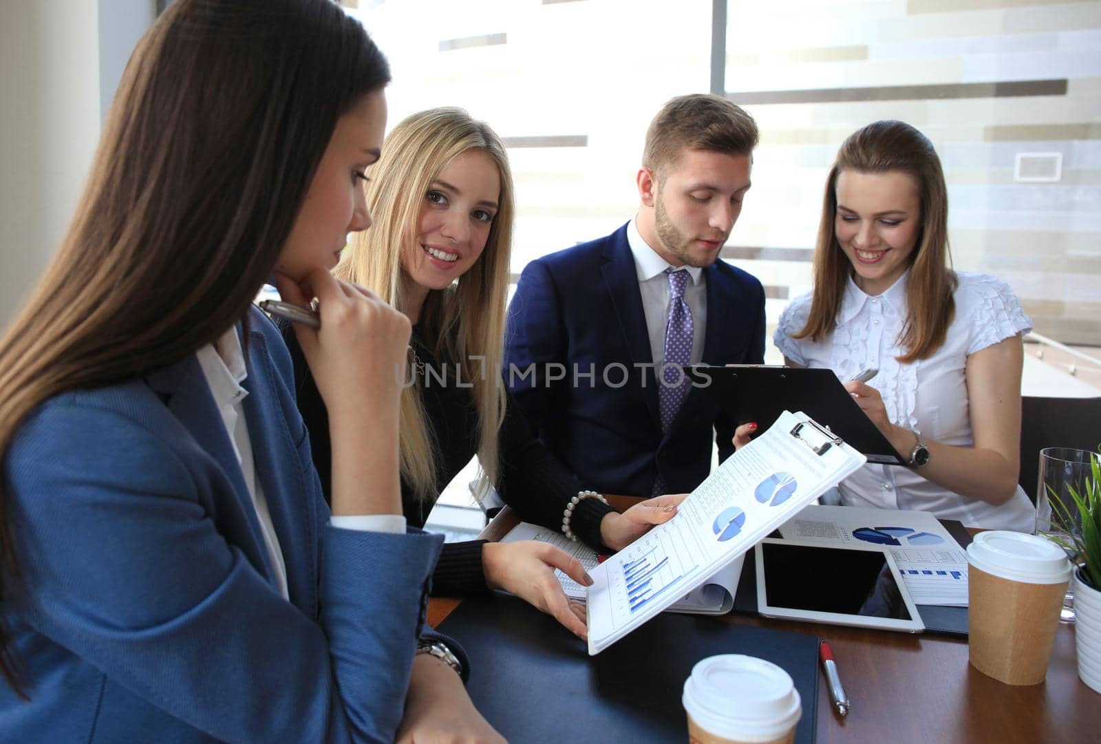 Image of four successful businesswomen looking at camera at meeting by tsyhun