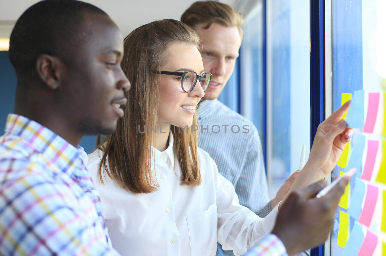 young creative startup business people on meeting at modern office making plans and projects with post stickers on glass