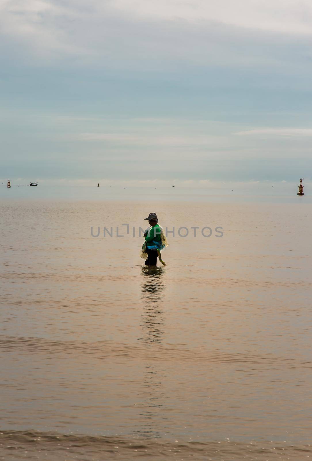 Phetchaburi, Thailand - Sep 19, 2021 : An unidentified local fisherman with his fishnet stands in the sea to catch some fish. Fisherman ready to cast fish net, No focus, specifically.