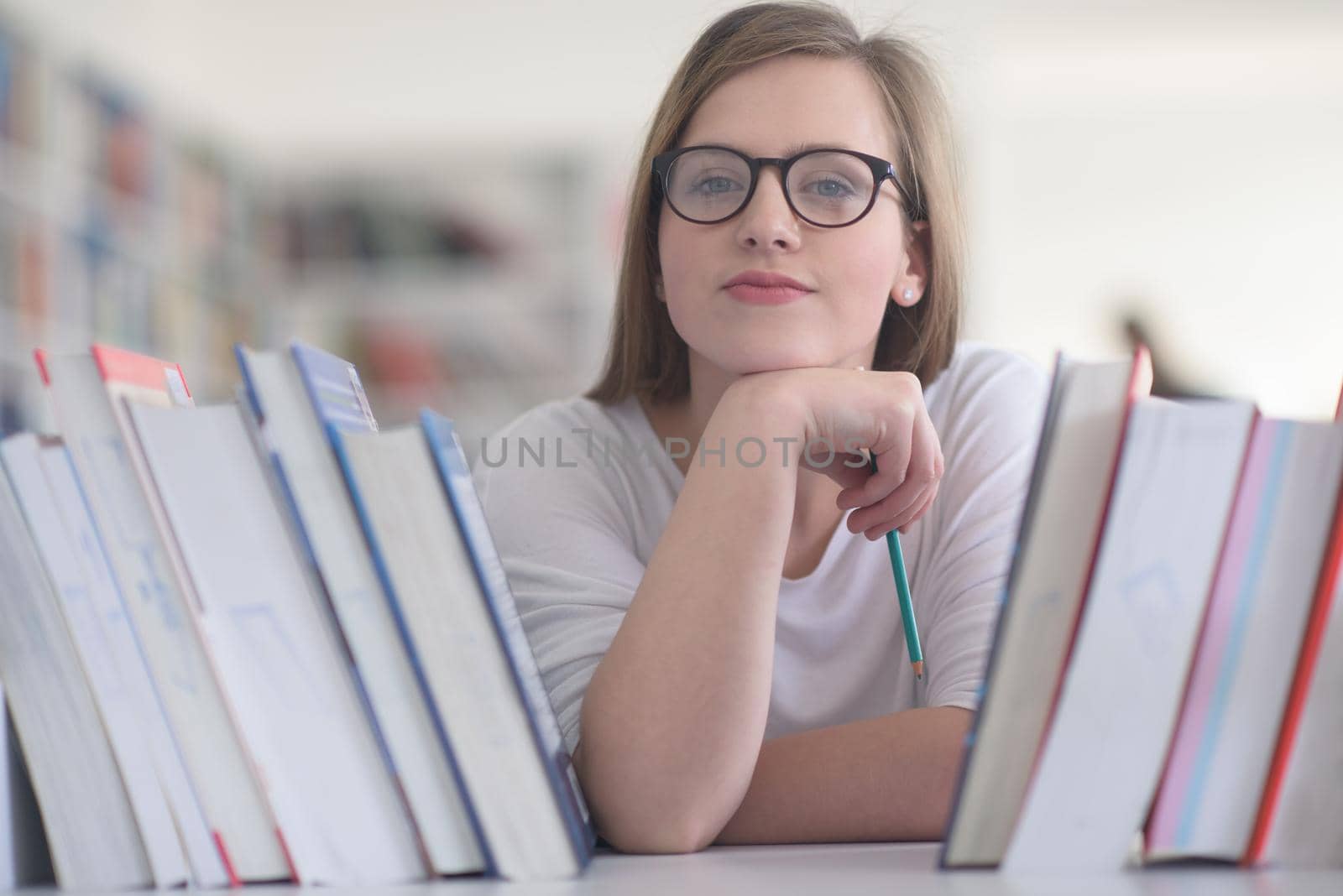 portrait of famale student selecting book to read in library by dotshock