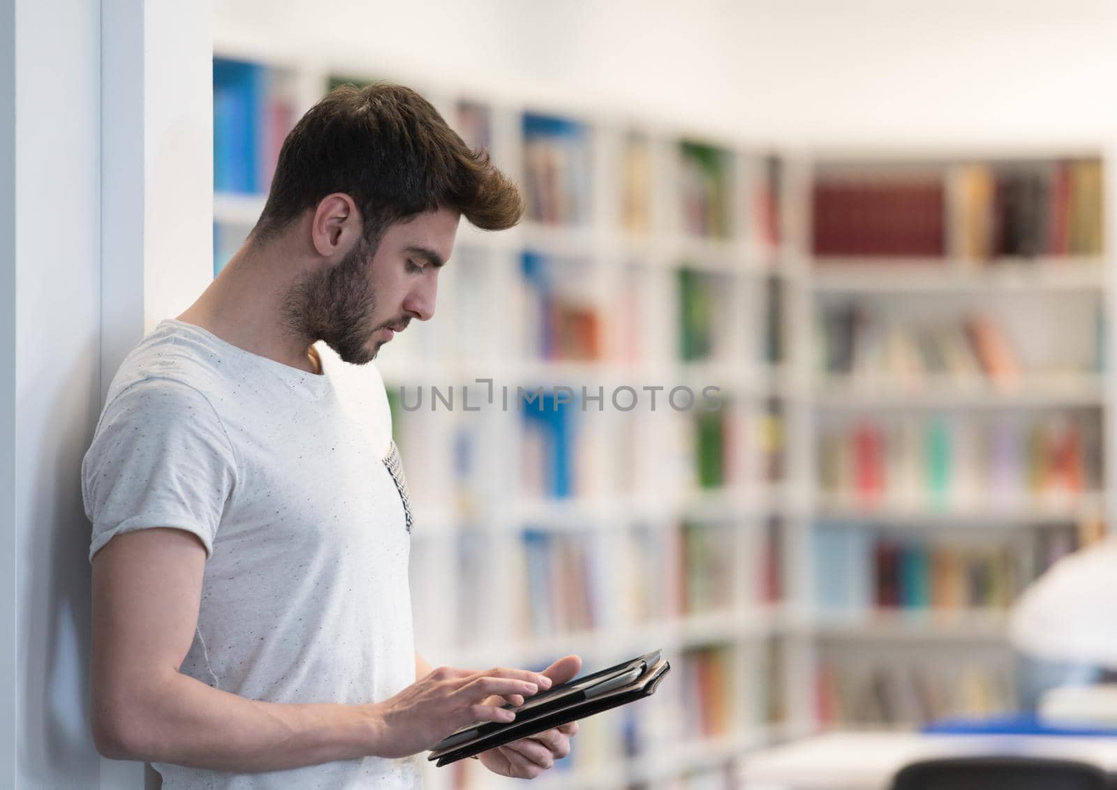 student in school library using tablet for research by dotshock