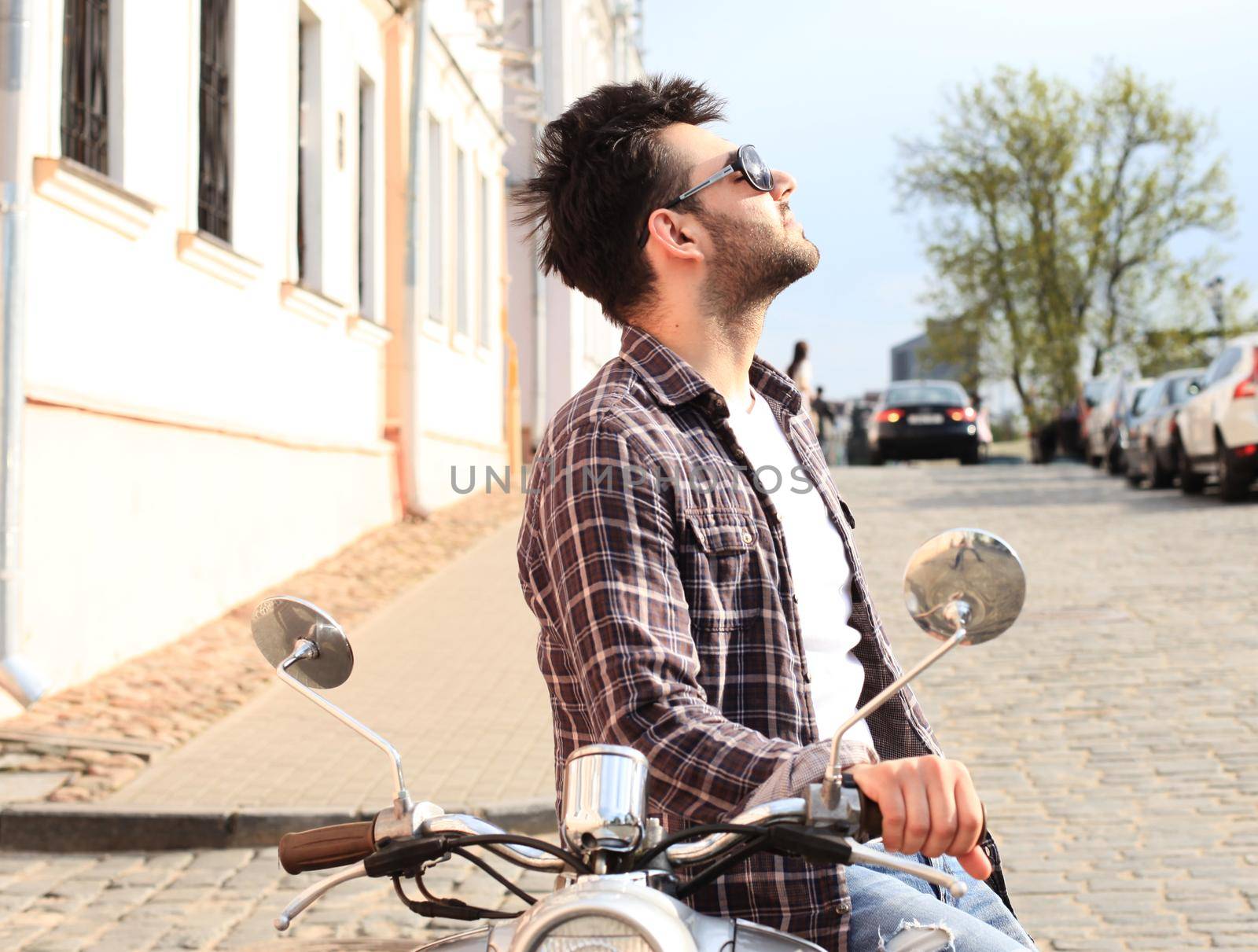 fashionable young man riding a vintage scooter in the street