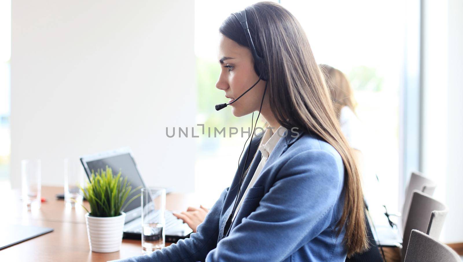 Portrait of call center worker accompanied by her team. Smiling customer support operator at work.