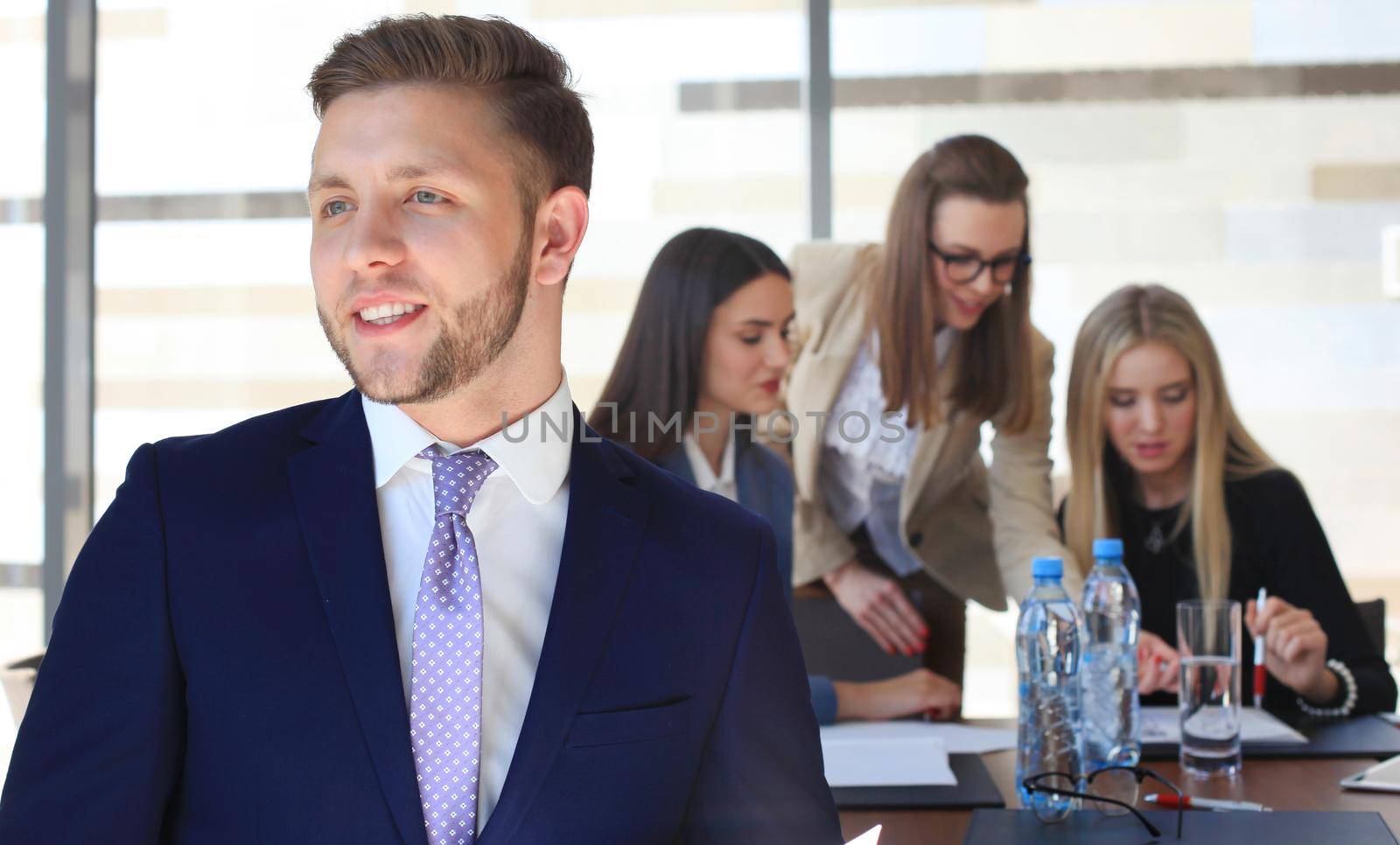 Happy smart business man with team mates discussing in the background