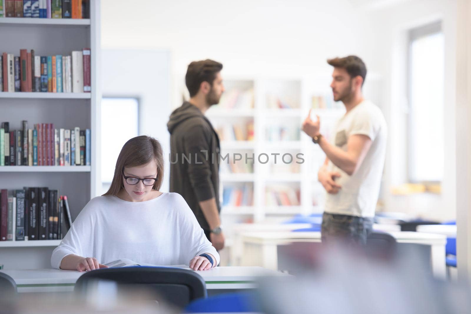 female smart looking student study in school library, group of students in background