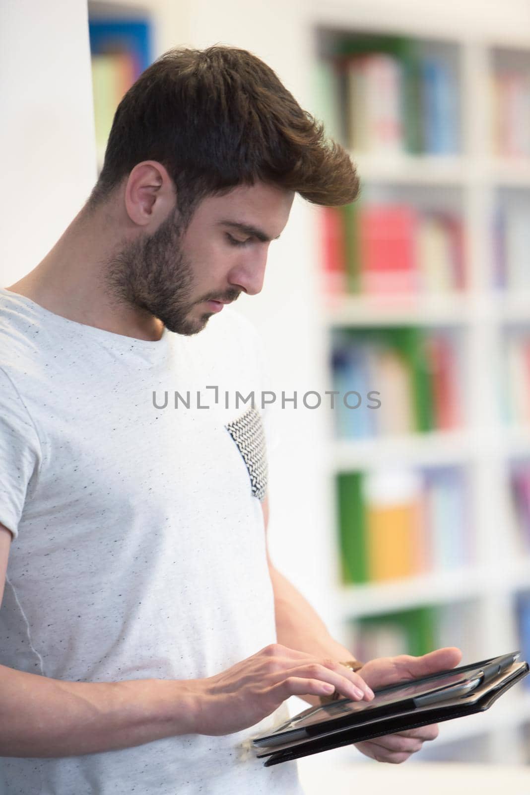 student preparing exam and learning lessons in school library, making research on tablet  and browse internet