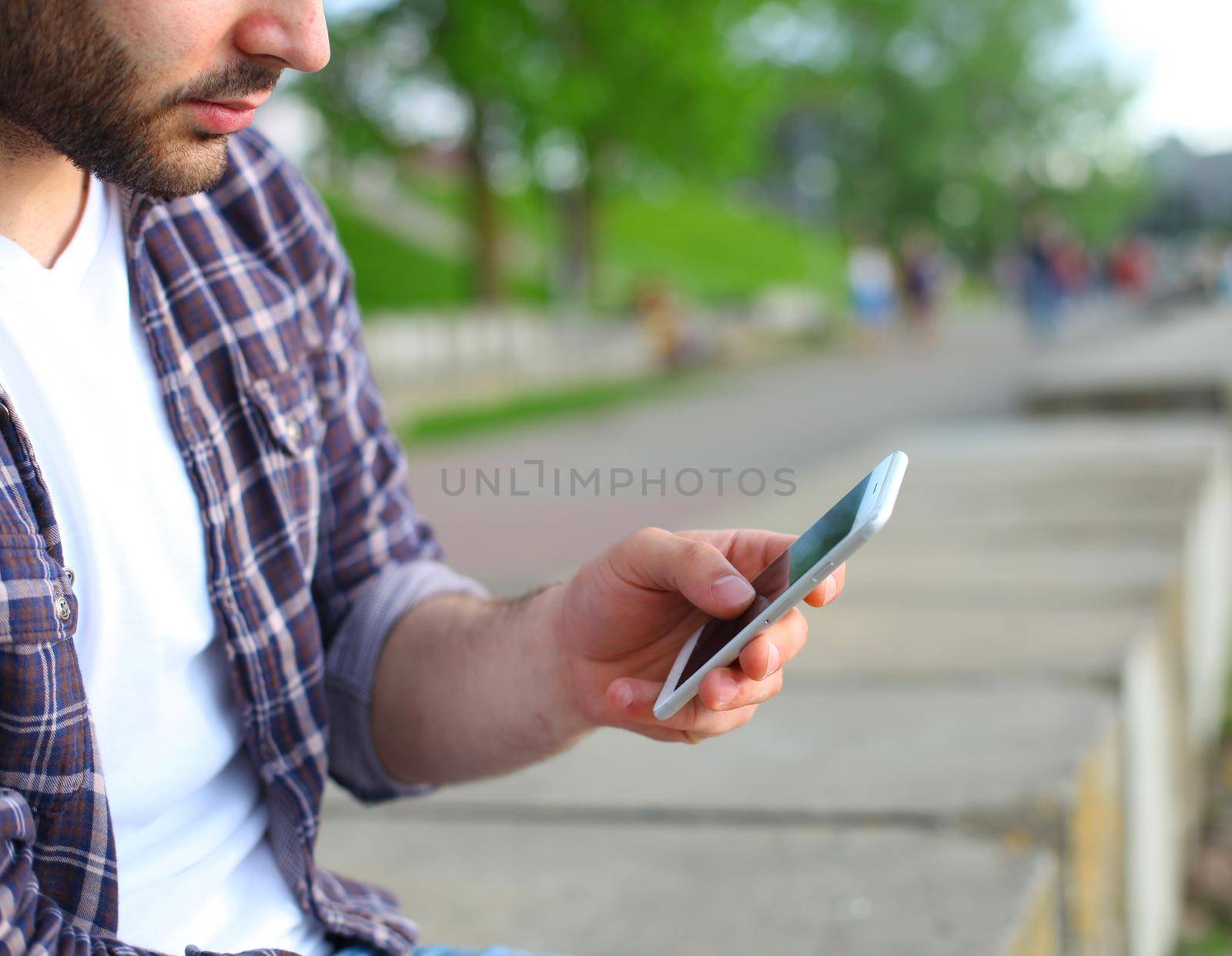 Man using his Mobile Phone outdoor, close up by tsyhun
