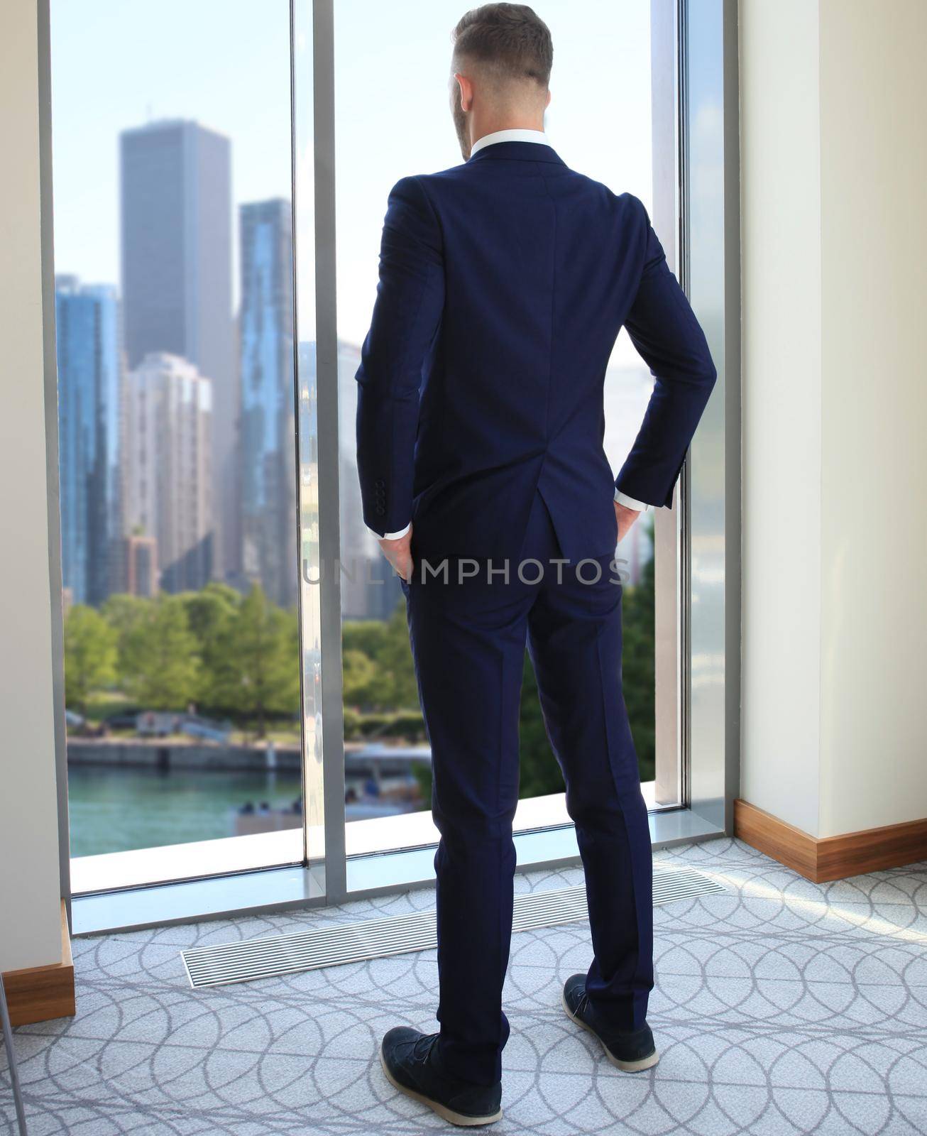 Back view of successful manager looking the city from his office