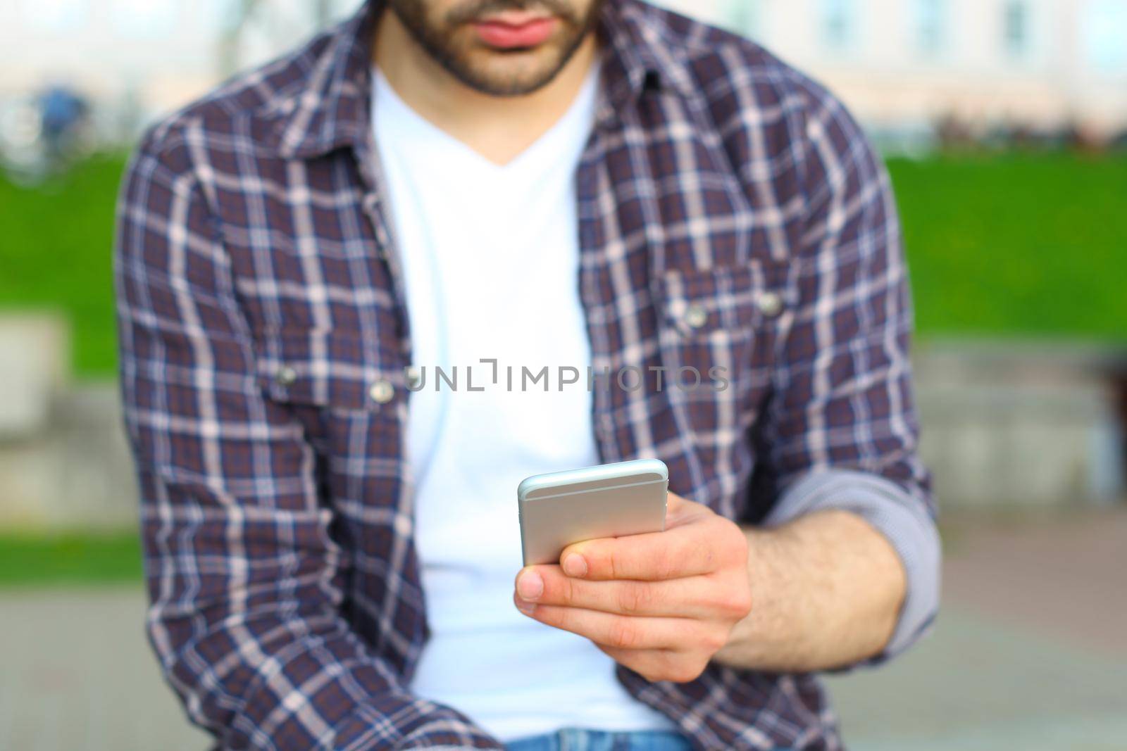 Man using his Mobile Phone outdoor, close up