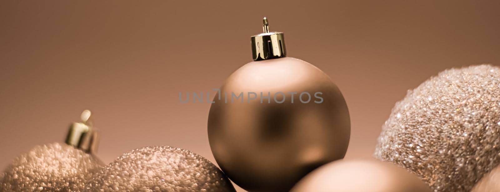 Christmas holiday and festive decoration concept. Golden baubles on beige background by Anneleven