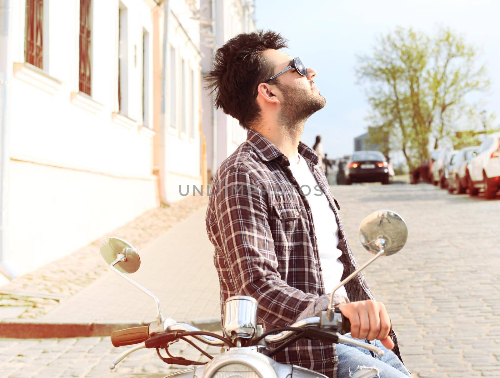 fashionable young man riding a vintage scooter in the street