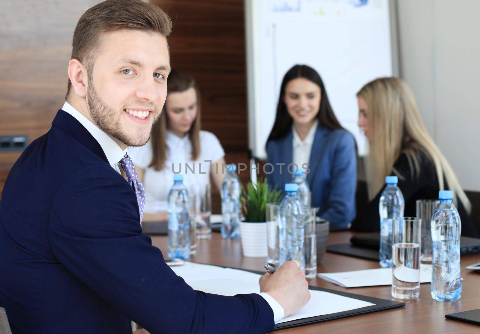 Happy smart business man with team mates discussing in the background