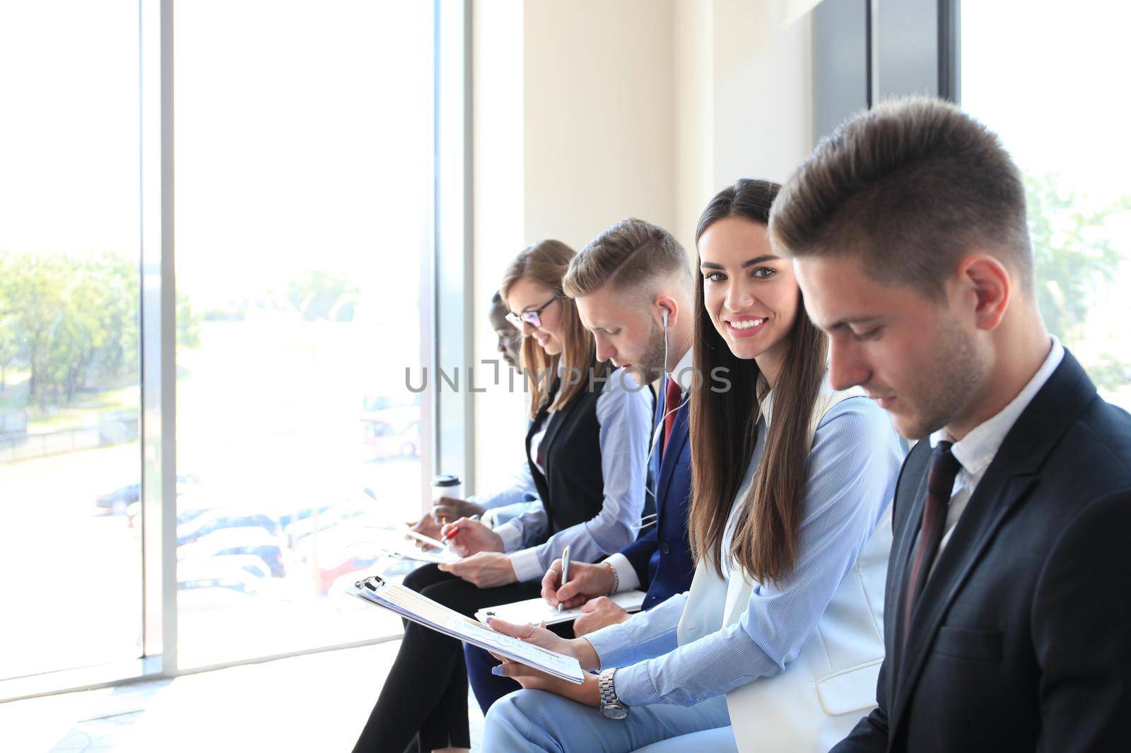 Smiling businesswoman looking at camera at seminar with her colleagues near by by tsyhun