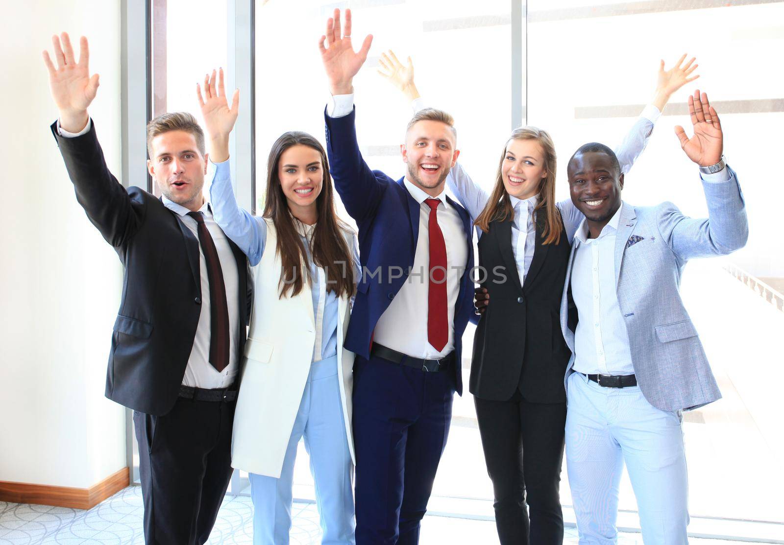 Portrait of successful business group waving hands in office by tsyhun