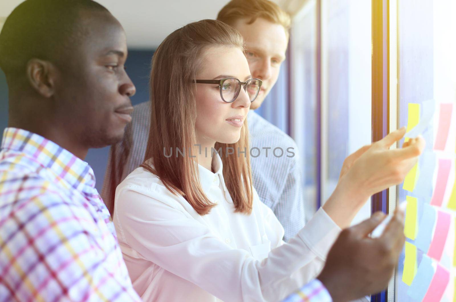 young creative startup business people on meeting at modern office making plans and projects with post stickers on glass