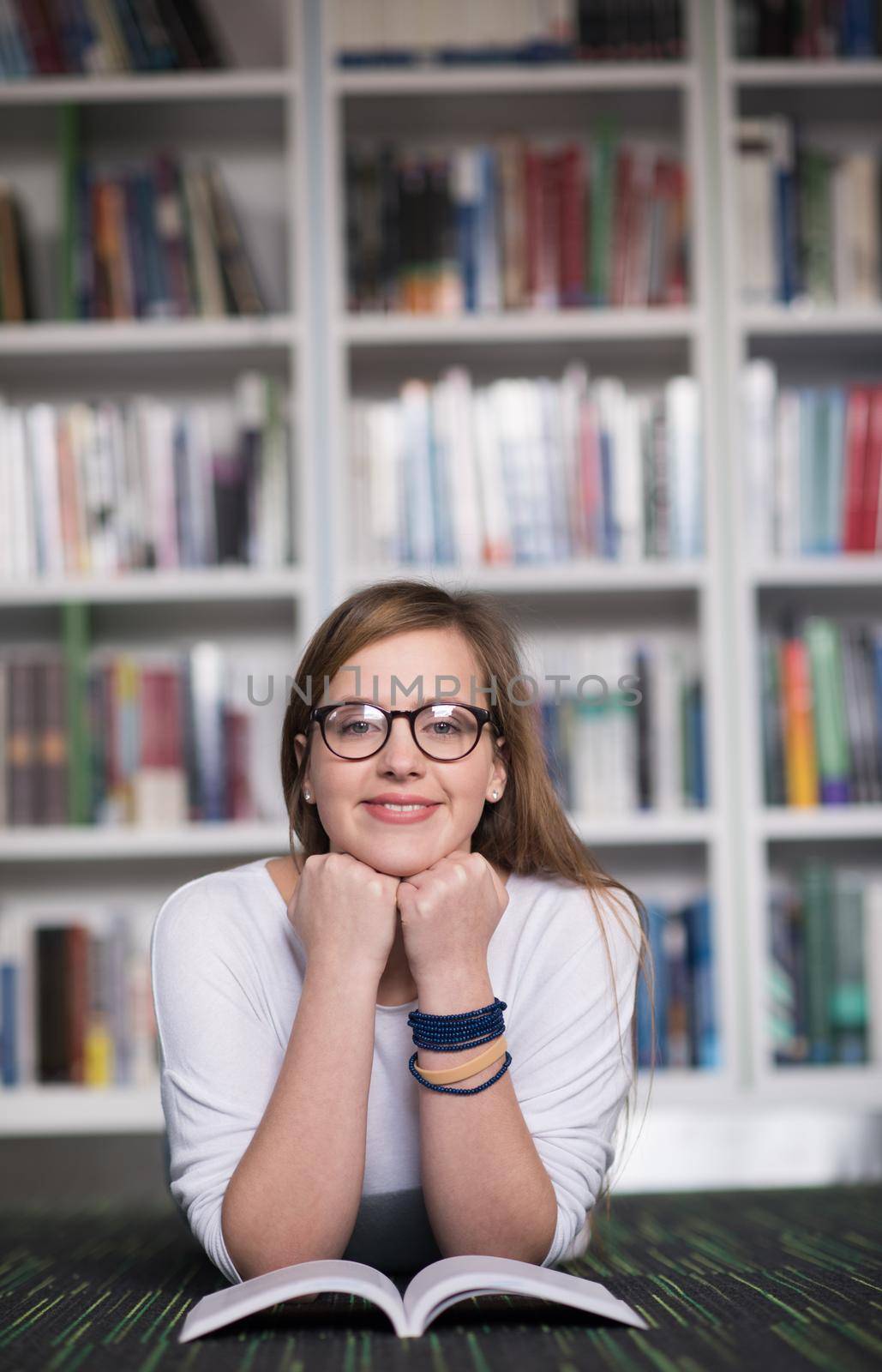 female student study in school library, using tablet and searching for information’s on internet. Listening music and lessons on white headphones