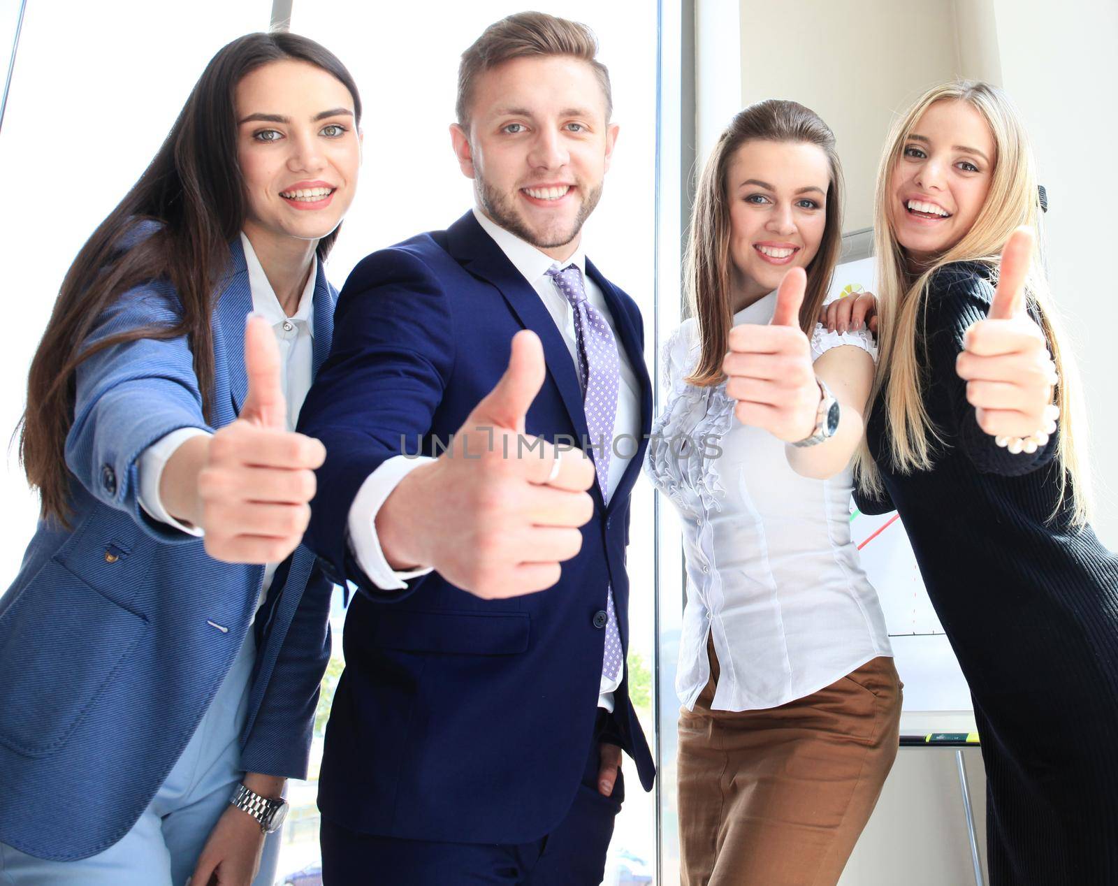 Portrait of happy businesspeople standing in office showing thumb up by tsyhun