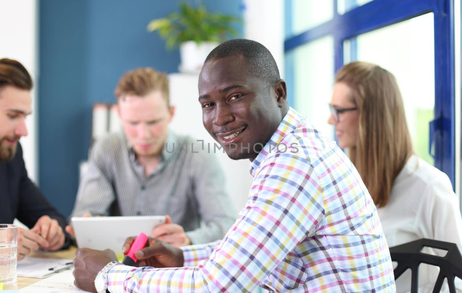 Portrait of smiling African American business man with executives working in background by tsyhun