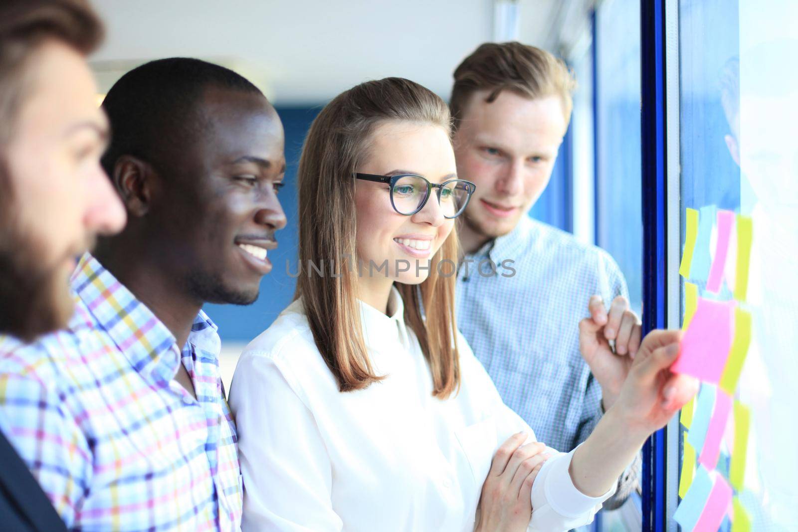 young creative startup business people on meeting at modern office making plans and projects with post stickers on glass