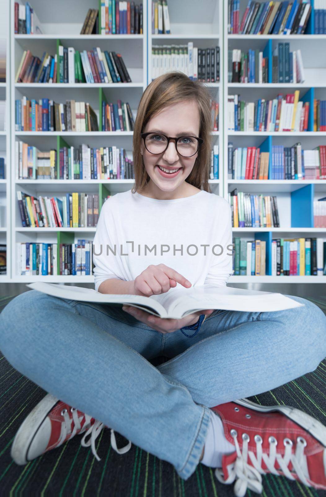 female student study in school library, using tablet and searching for information’s on internet. Listening music and lessons on white headphones