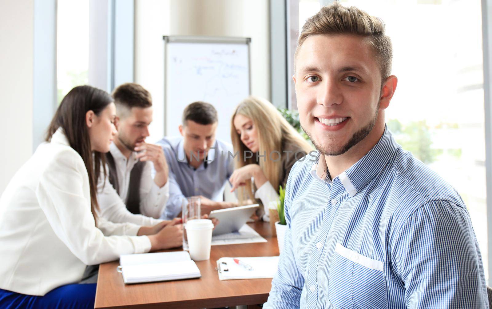 Businessman with colleagues in the background in office.